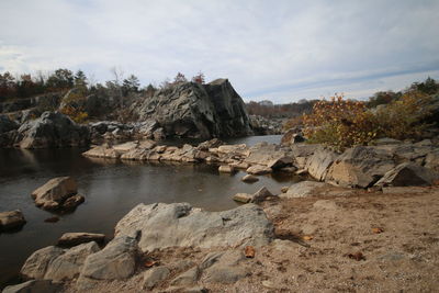 Rocks by trees against sky