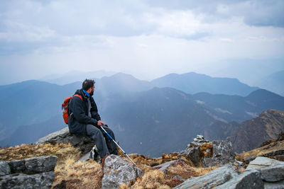 Man sitting on rocks against mountains
