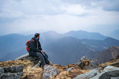 People on rocks against mountains