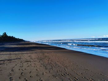 Scenic view of beach against clear blue sky