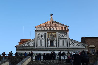 Group of people against building against clear blue sky