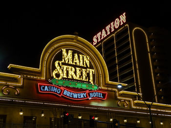 Low angle view of illuminated text against sky at night