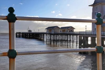 Pier on sea by building against sky