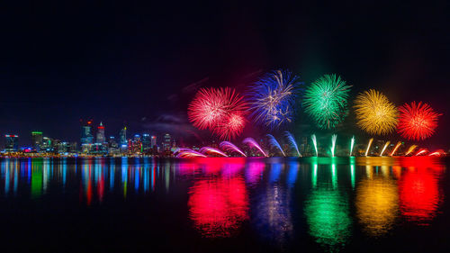 Illuminated firework display over river at night