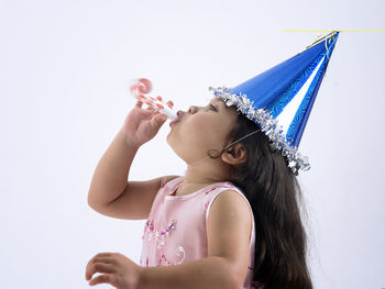 Girl blowing whistle against white background