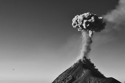 Low angle view of smoke emitting from volcanic mountain against sky