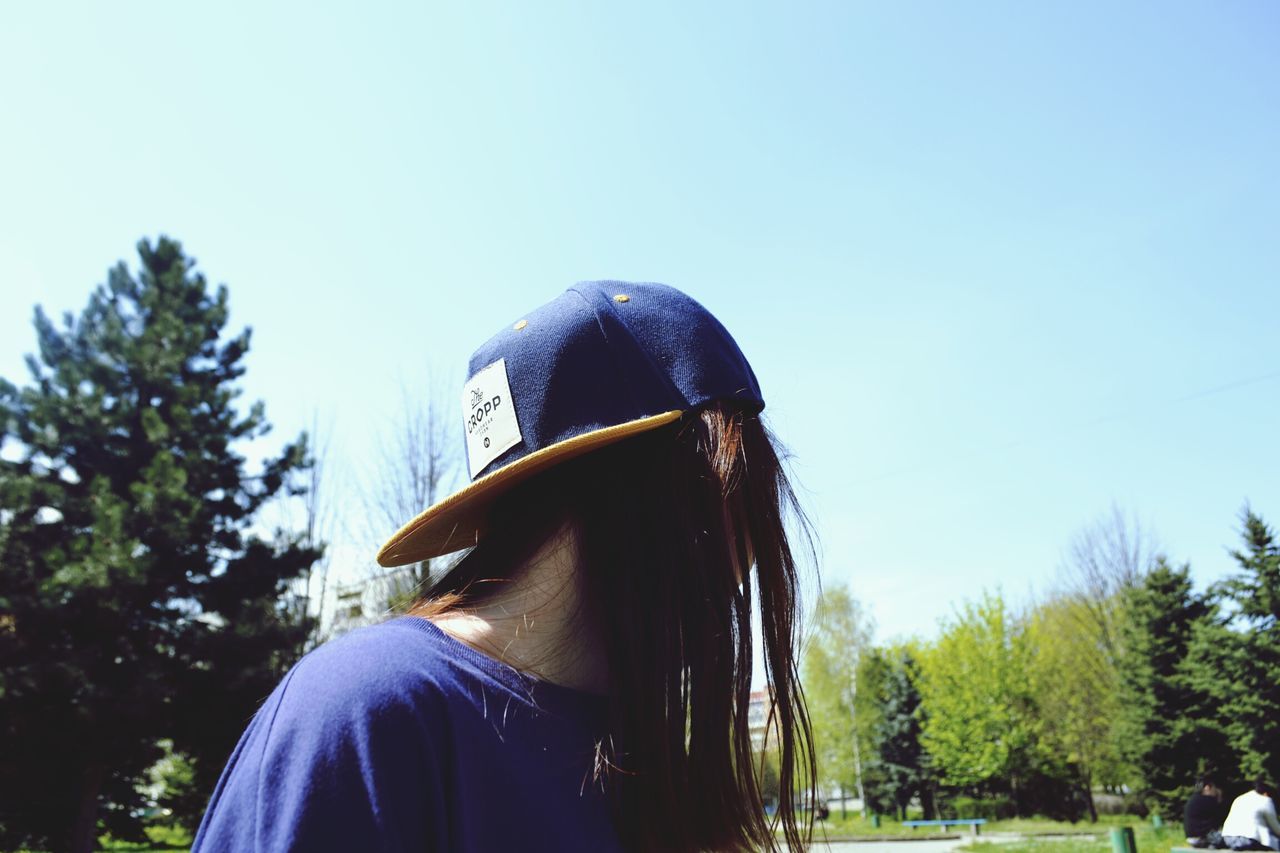 LOW ANGLE VIEW OF WOMAN STANDING ON TREE