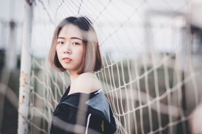 Portrait of beautiful young woman standing at goalpost