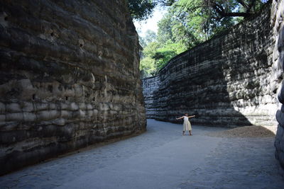 Full length of girl standing amidst retaining wall