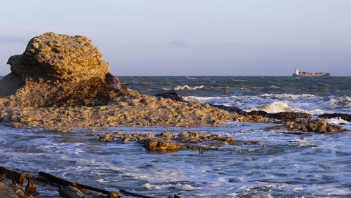 Rocks on sea shore against sky