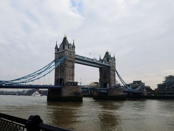 Tower bridge over river against cloudy sky in london, england