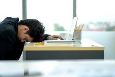 Side view of man sitting on table