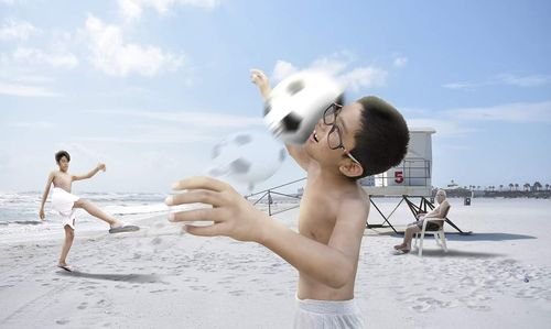 Side view of siblings playing on beach against sky