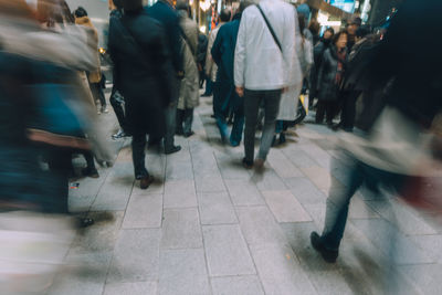 Low section of people walking on street in city