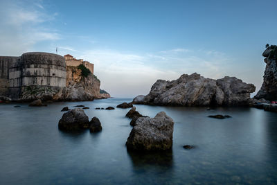 Rocks by sea against sky