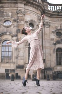 Full length of woman with arms raised in city