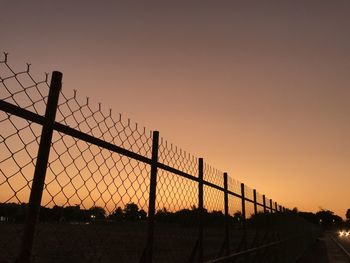 Silhouette fence against clear sky during sunset