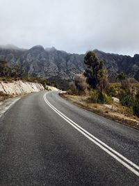 Empty road by mountain against sky