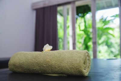 Close-up of flower and rolled towel on table
