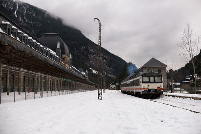 Snow covered railroad tracks by mountain against sky