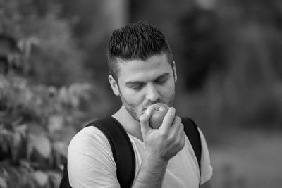 Young man holding apple standing outdoors