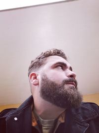 Bearded man looking away against wall