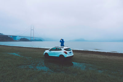 Man on bridge over sea against sky