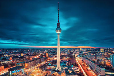 Communications tower in city against sky at night