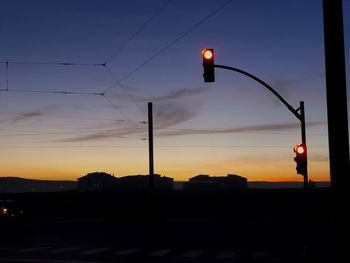 Silhouette street lights against sky during sunset