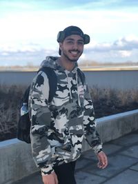 Portrait of smiling man standing against sky