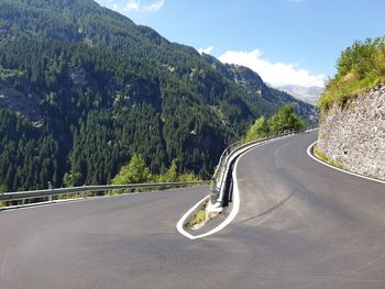 Car moving on road by mountain against sky