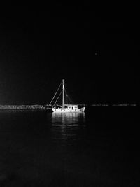 Illuminated suspension bridge over sea against clear sky