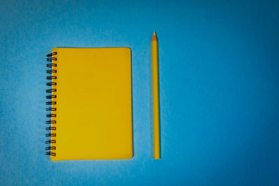 High angle view of yellow colored pencils against blue background