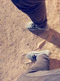 Low section of woman standing on sand at beach