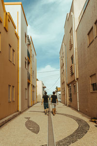 Rear view of people walking on road amidst buildings