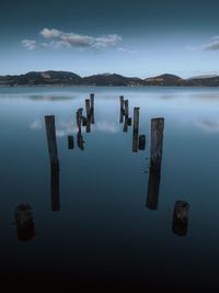 High angle view of wooden posts in lake against sky