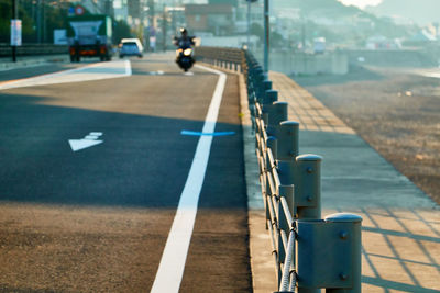 View of man riding motorcycle on road by the beach