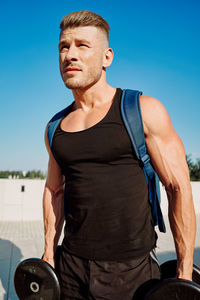 Low angle view of young man exercising against sky