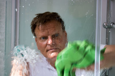 Close-up of mature man washing glass window