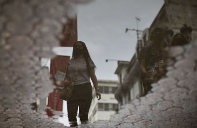 Rear view of woman standing amidst buildings in city