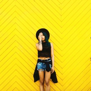 Portrait of young woman standing on wall