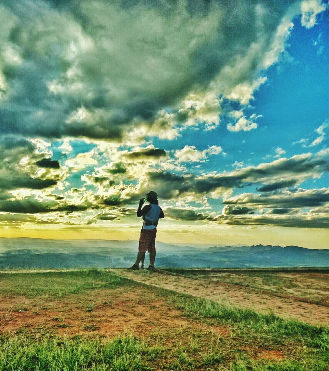sky, rear view, full length, cloud - sky, standing, grass, tranquility, lifestyles, landscape, leisure activity, field, tranquil scene, cloud, nature, cloudy, beauty in nature, casual clothing, scenics