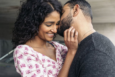 Man kissing woman against wall