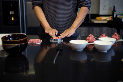 Midsection of man shaping meat at kitchen
