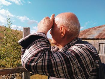 Man with arms raised against sky