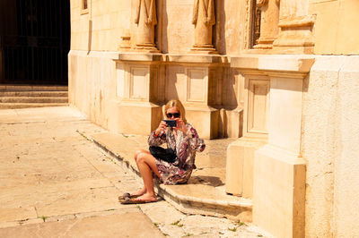 Full length of woman sitting outside historic building