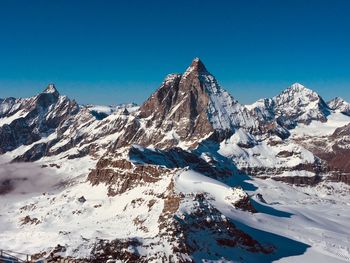 Scenic view of snowcapped mountains against clear blue sky