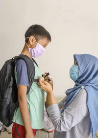 A hijab woman and her son are wearing masker before going out to school in covid 19 pandemic