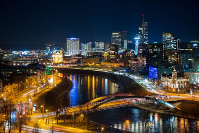 Illuminated bridge and buildings against sky at night