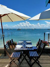 Chairs and tables at restaurant by sea against blue sky in cap ferret in france 